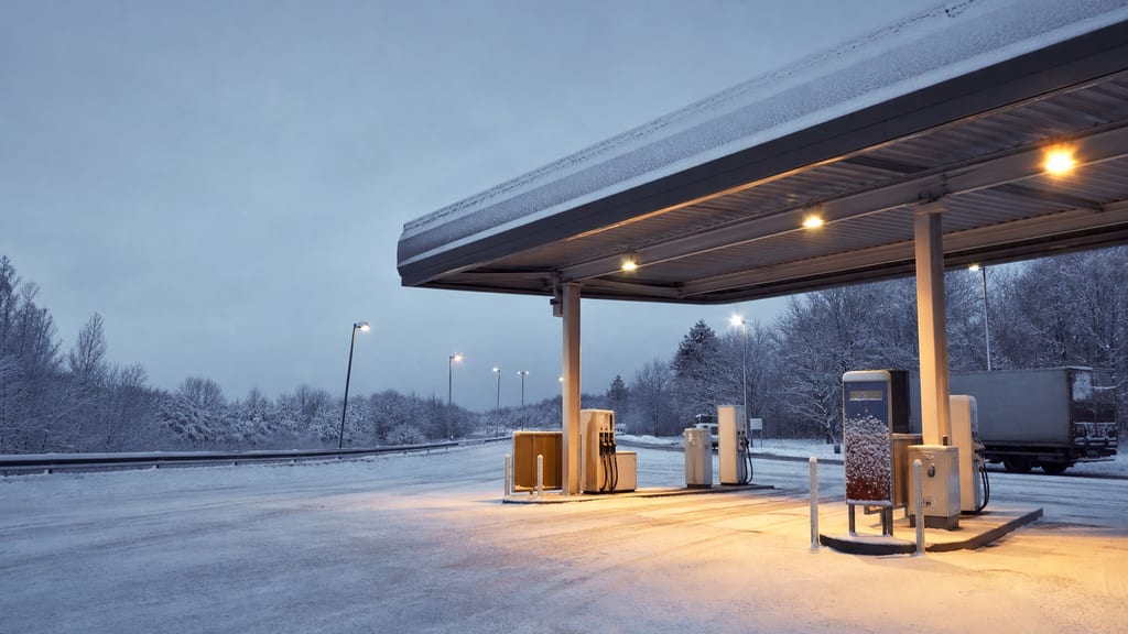Station d’aire d’autoroute sous la neige en France, auvent éclairé — prix carburant Esso — A71aire de Ste Thorette à Marmagne près d’une autoroute
